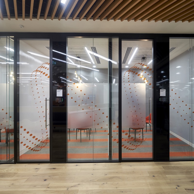 Alt text: Large glass doors with black frame in an office space. 