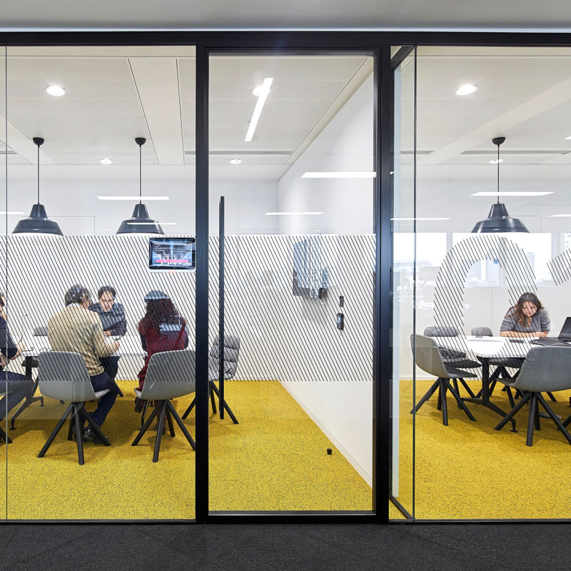 Alt text: Black frame glass walls surround and divide office spaces.