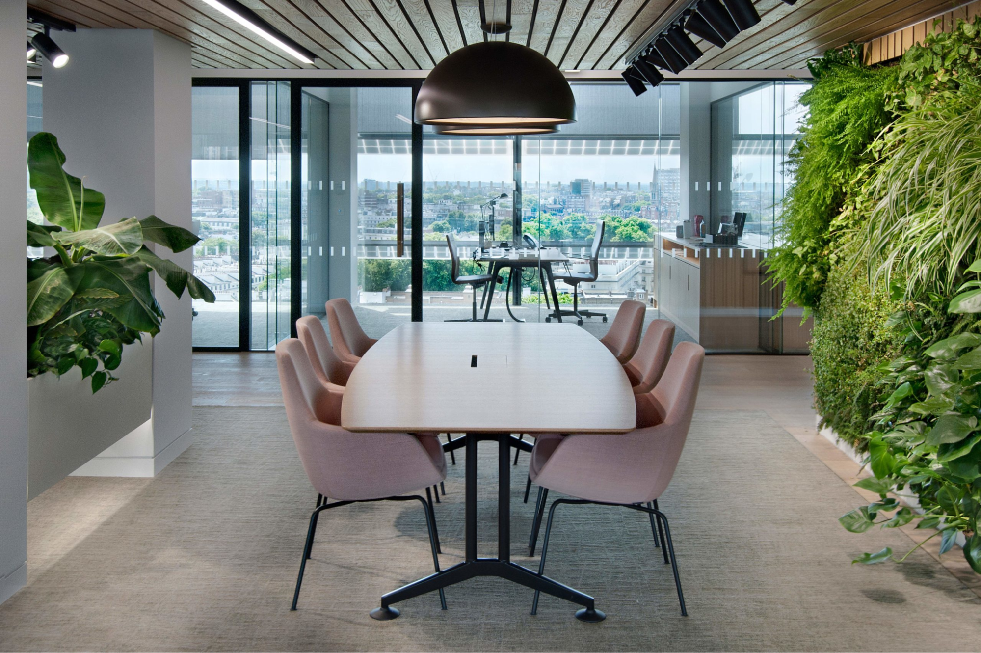 an office with a lot of greenery that compliments the glass doors design